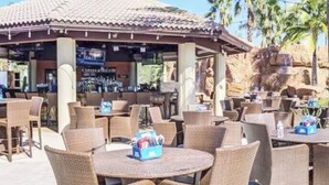 Een terras met rieten meubilair en een bar op de achtergrond.