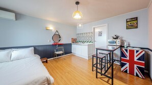 Ein Zimmer mit einem Bett, einem kleinen Tisch, einem Stuhl, einer Küchenzeile und einem Wandradiator.