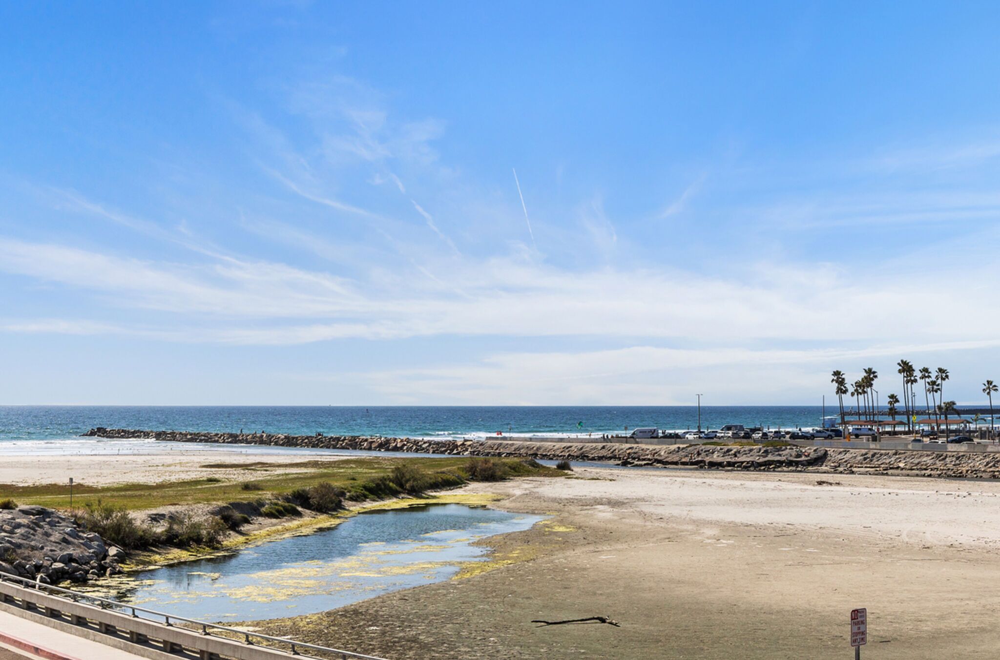 Una playa con costa rocosa, una pequeña extensión de agua y vista distante del océano.
