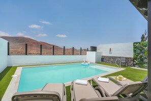 Piscina con sillas de descanso, un flotador con forma de cisne y vistas a montañas.