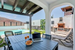 Une terrasse avec piscine, un espace salon extérieur et un coin barbecue.