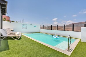 Une piscine avec un panneau indicateur, des chaises longues et une vue sur les collines.