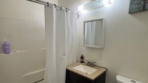 Um banheiro com banheira, pia, vaso sanitário e espelho.