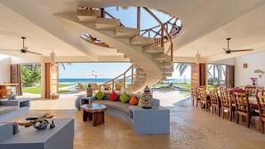 A spacious living area with a spiral staircase, a dining area, and a view of the ocean. - Casa STÁA OCEANFRONT PUERTO ESCONDIDO, PRIVACY OCEANFRONT HOUSE (SANTA MARIA COLOTEPEC)