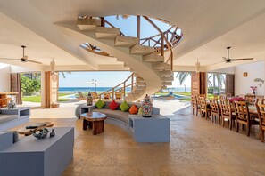 A spacious living area with a spiral staircase, a dining area, and a view of the ocean.
