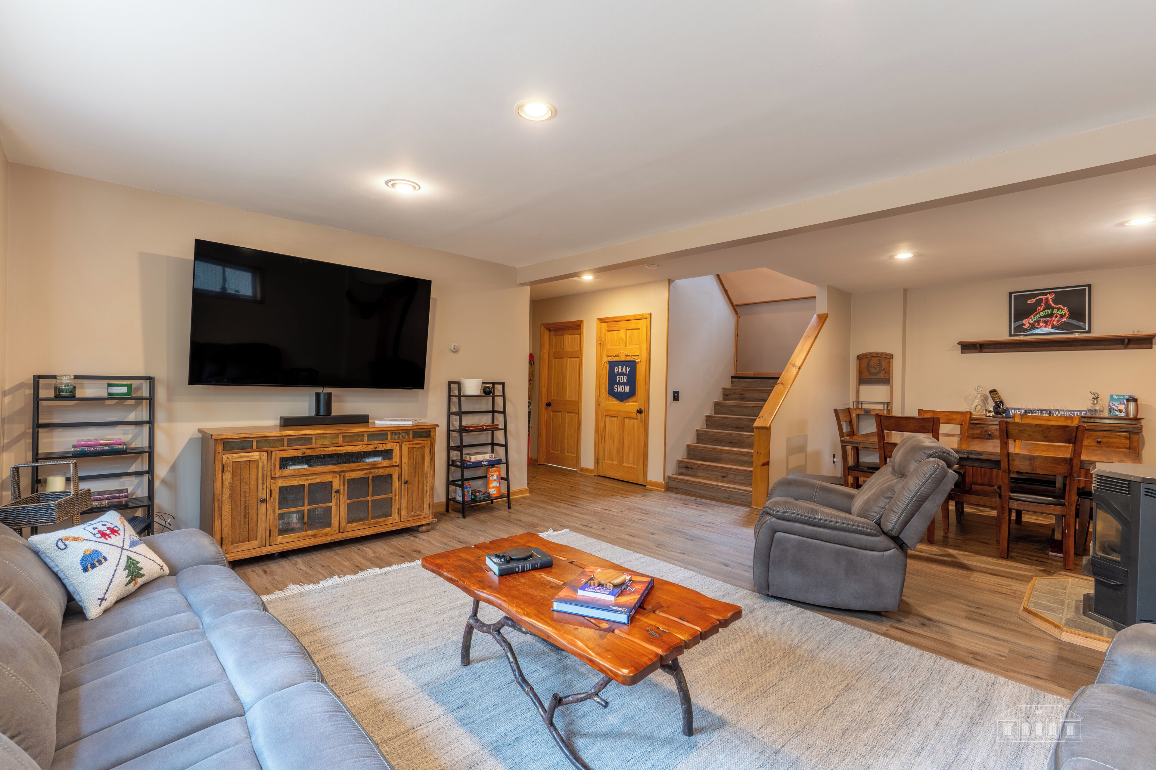 A living room with a sofa, a coffee table, a television, a fireplace, and a staircase leading to another room.