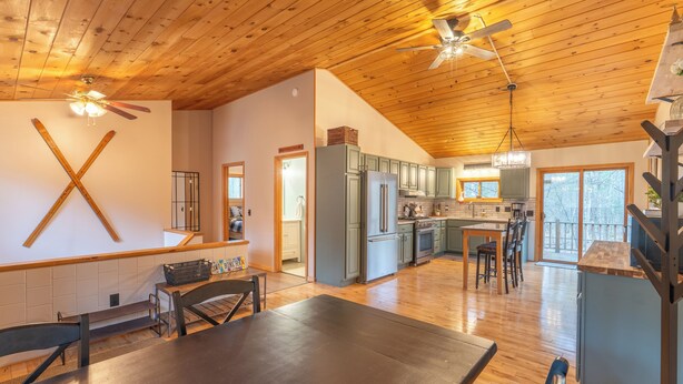 Un'ampia cucina con mobili in legno, un'area pranzo con tavolo e sedie e una ventola a soffitto.