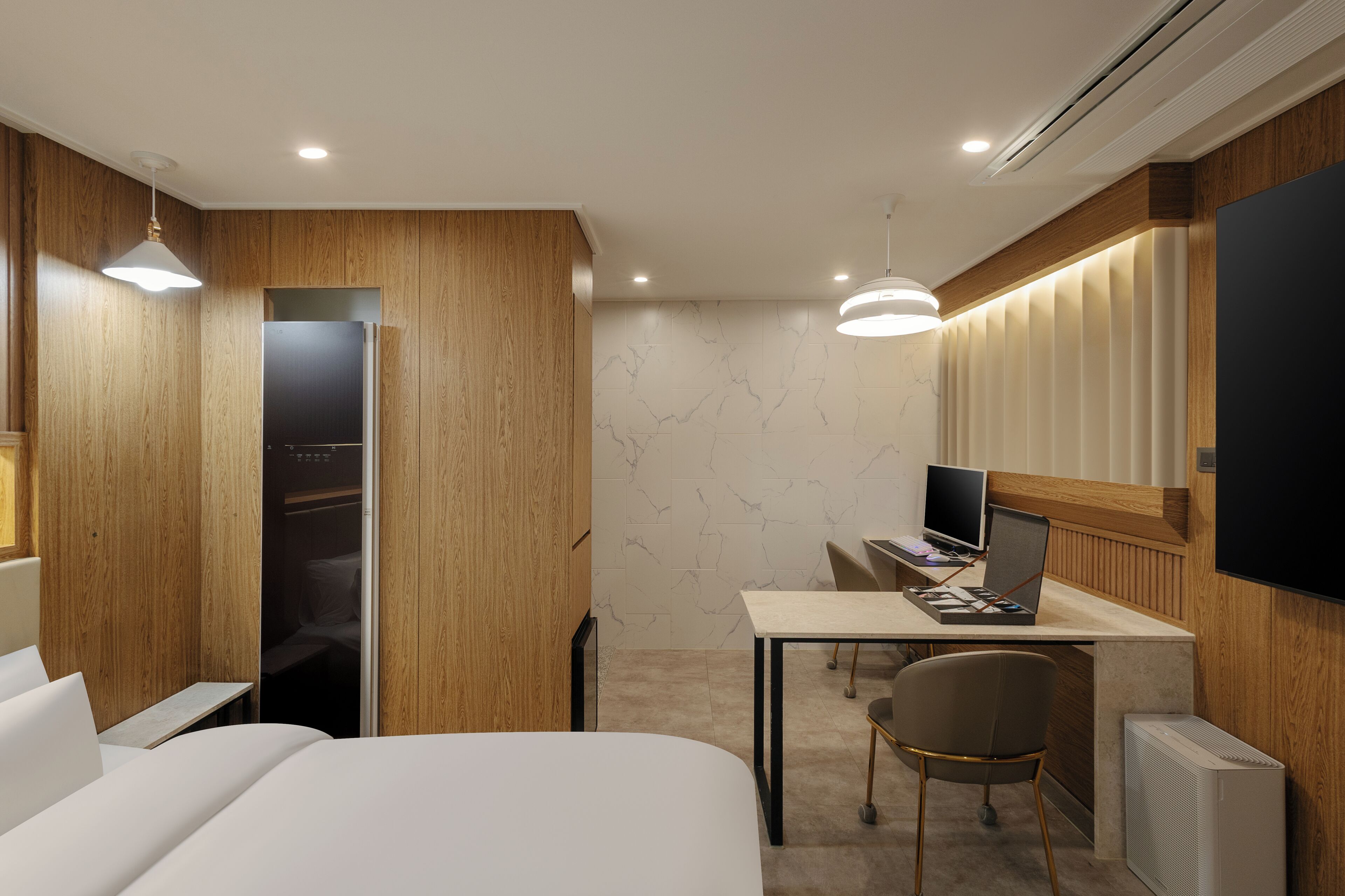 Una habitación de hotel moderna con cama, escritorio, silla y armario.