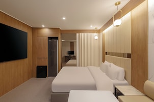 A modern hotel room with a large bed, a flat-screen TV, and a seating area with a table.