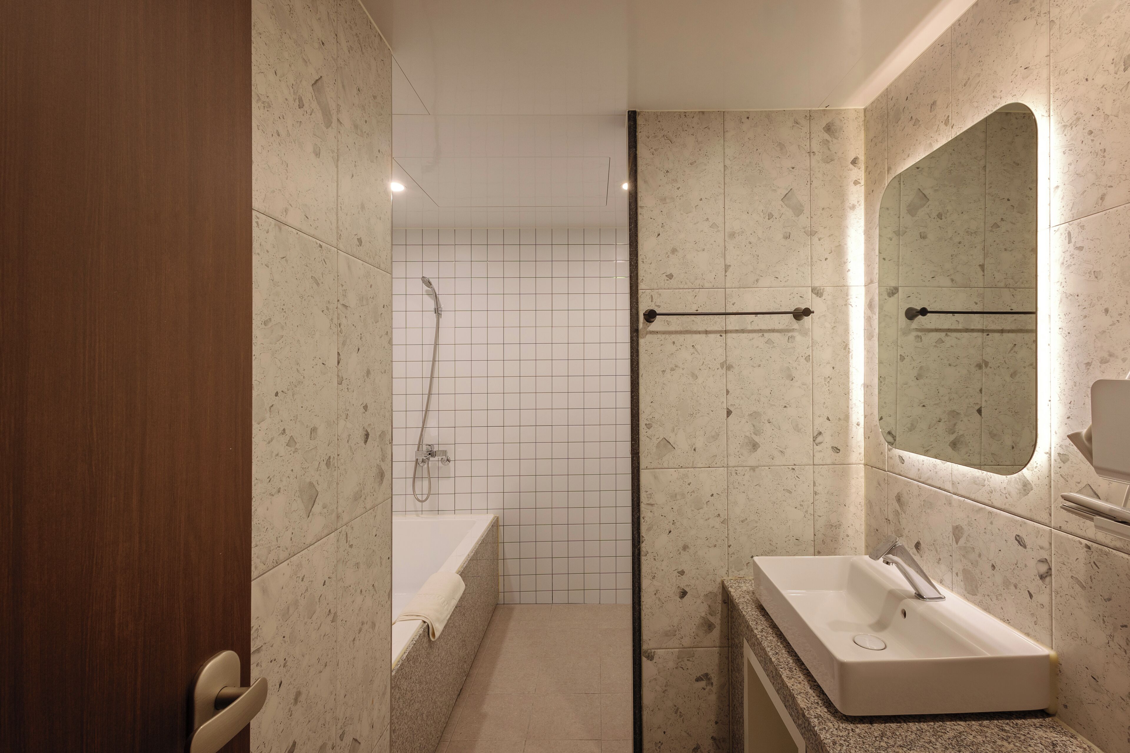 Un baño moderno con ducha, lavamanos y espejo.