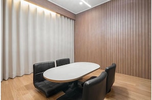A conference room with a wooden table and black leather chairs, a wooden wall panel, and a white curtain. - BROWNDOT HOTEL ANDONG OKDONG (Andong)