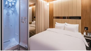 Et hotelværelse med seng, træsengegavl, indbygget skab og minibar.