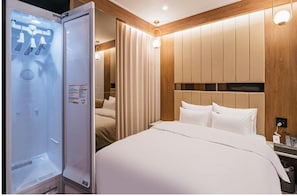 Una habitación de hotel con una cama, cabecera de madera, armario empotrado y minibar.