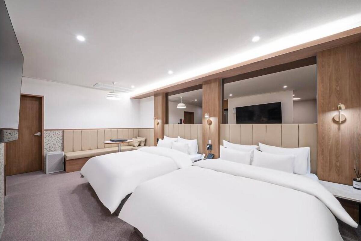Ein Hotelzimmer mit zwei Betten, einer Couch, einem kleinen Tisch und einem Spiegel.