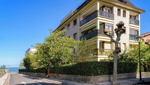 A multi-story residential building with balconies, a paved street, and a clear view of the sea. - Loft Penthouse on the Beach With 2 Terraces (Zarautz)
