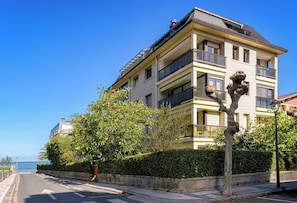 A multi-story residential building with balconies, a paved street, and a clear view of the sea. - Loft Penthouse on the Beach With 2 Terraces (Zarautz)