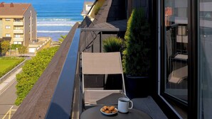 A balcony with a table, a cup, and cookies, overlooking the ocean and a building. - Loft Penthouse on the Beach With 2 Terraces (Zarautz)