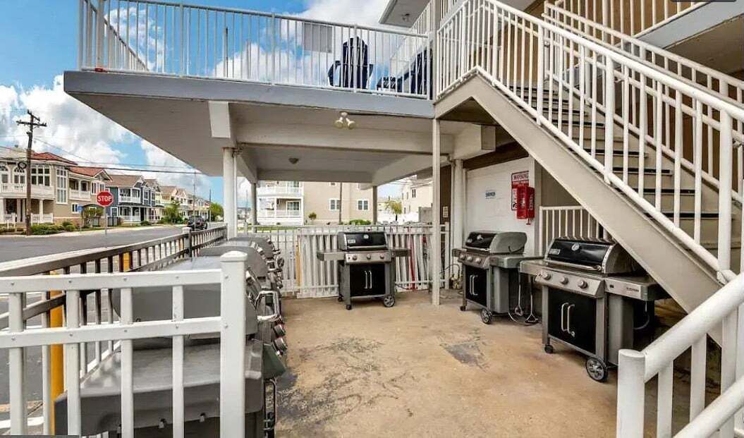 Ein überdachter Außenbereich mit Grillanlagen, einer Treppe und einem Stoppschild im Hintergrund.