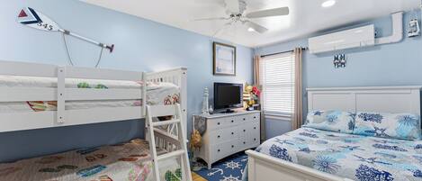 A bedroom with bunk beds, a TV, a dresser, and a ceiling fan.