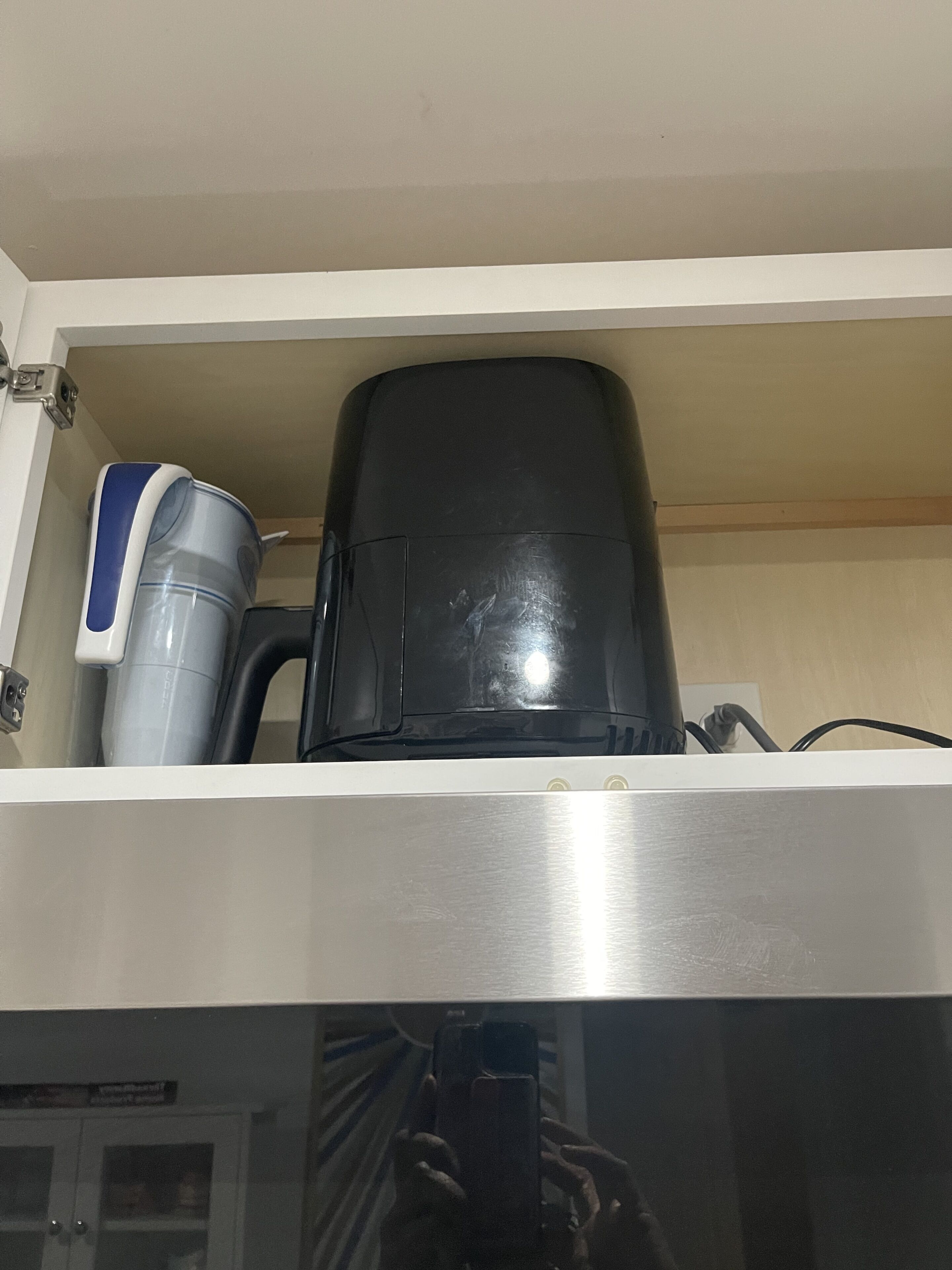 Eine Küche mit einer Kaffeemaschine und einem schwarzen Behälter auf der Arbeitsfläche.
