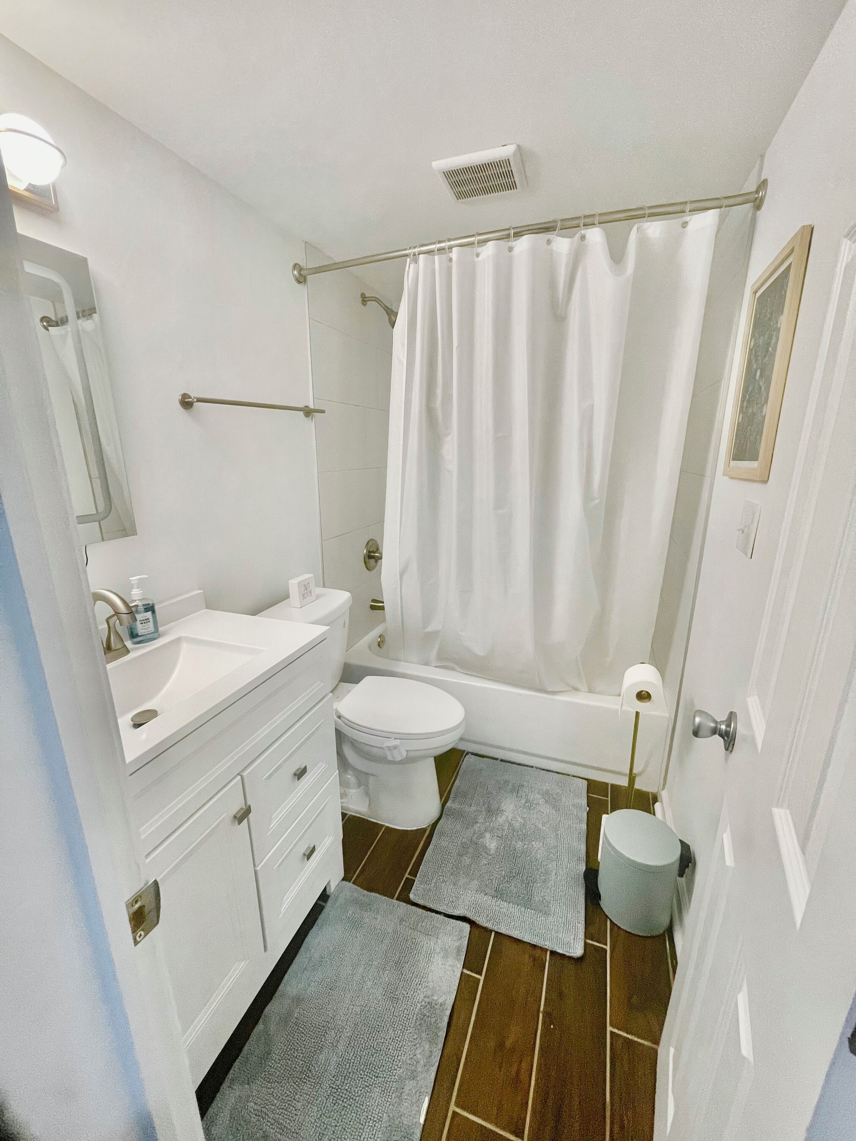Ein Badezimmer mit Toilette, Waschbecken, Badewanne, Duschvorhang und Spiegel.