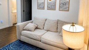 Ett vardagsrum med en soffa, en lampa och konst på väggen.