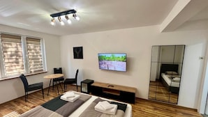 Moderni hotellihuone, jossa on suuri sänky, televisio, työpöytä ja peili.