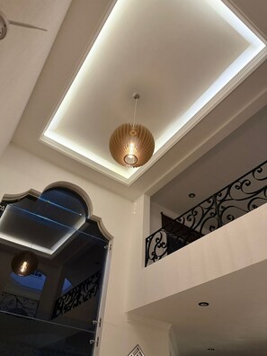 Un interior modern amb un fanal, una làmpada decorativa al sostre i un balcó amb barana ornamentada.
