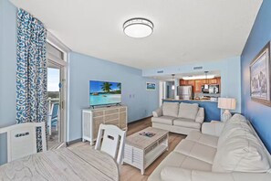 Ein Wohnzimmer mit Fernseher, einer Couch und einem Essbereich.
