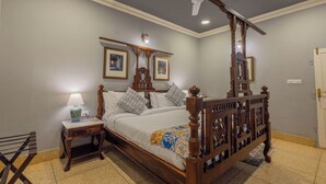 A four-poster bed with a wooden headboard, a nightstand with a lamp, and a ceiling fan. - Sheel Mahal Near Hawa Mahal (Jaipur)
