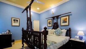 A bedroom with a four-poster bed, a nightstand with a lamp, a dresser, and framed pictures on the walls. - Sheel Mahal Near Hawa Mahal (Jaipur)