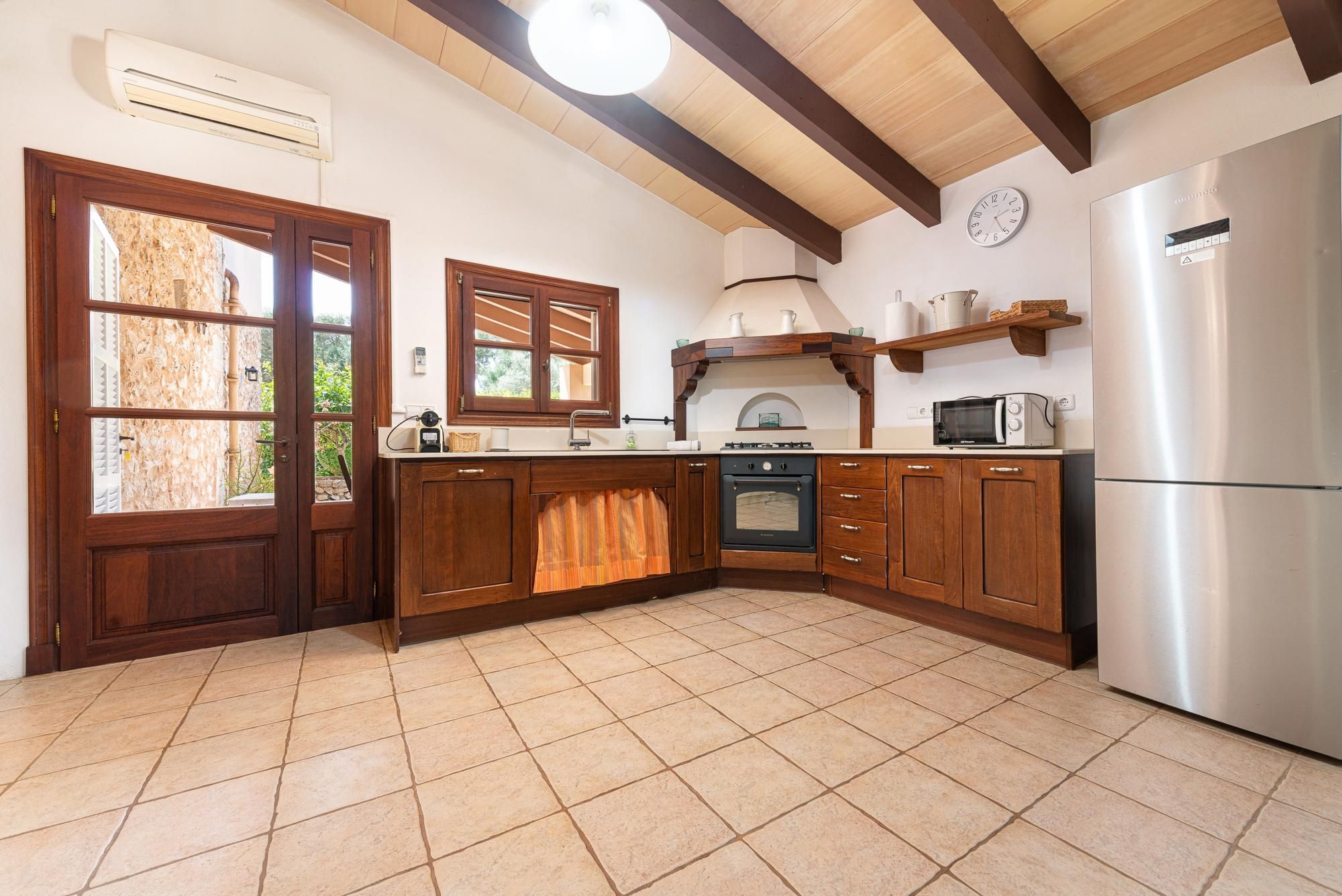 Una cocina con armarios de madera, horno empotrado, microondas y refrigerador.