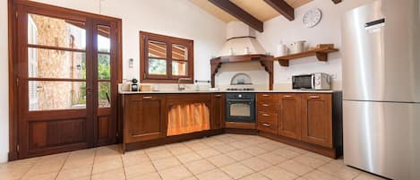 Una cocina con armarios de madera, horno empotrado, microondas y refrigerador.
