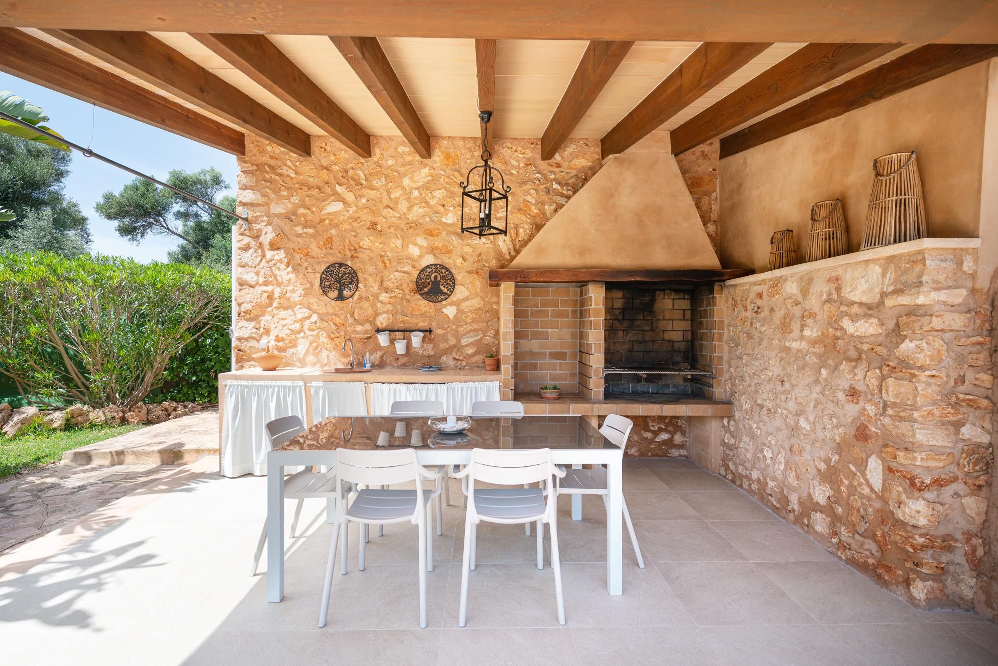 An outdoor patio with a stone wall, a brick fireplace, and a dining table with chairs.