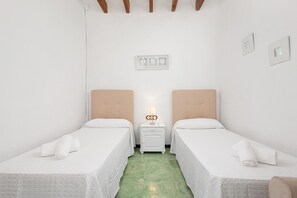 A room with two beds, a nightstand with a lamp, and a wall-mounted light switch. - CAN PUIG - Lovely house with private pool and free Wi-Fi (Santanyí)