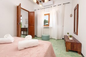 A bedroom with a bed, a bedside table, a window with curtains, and a radiator. - CAN PUIG - Lovely house with private pool and free Wi-Fi (Santanyí)