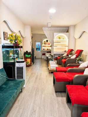 A modern interior with a sofa, a massage chair, a fish tank, and a well-lit room. - Movida Stay - Bui Vien Walking Street, District 1 (Thanh Pho Ho Chi Minh)