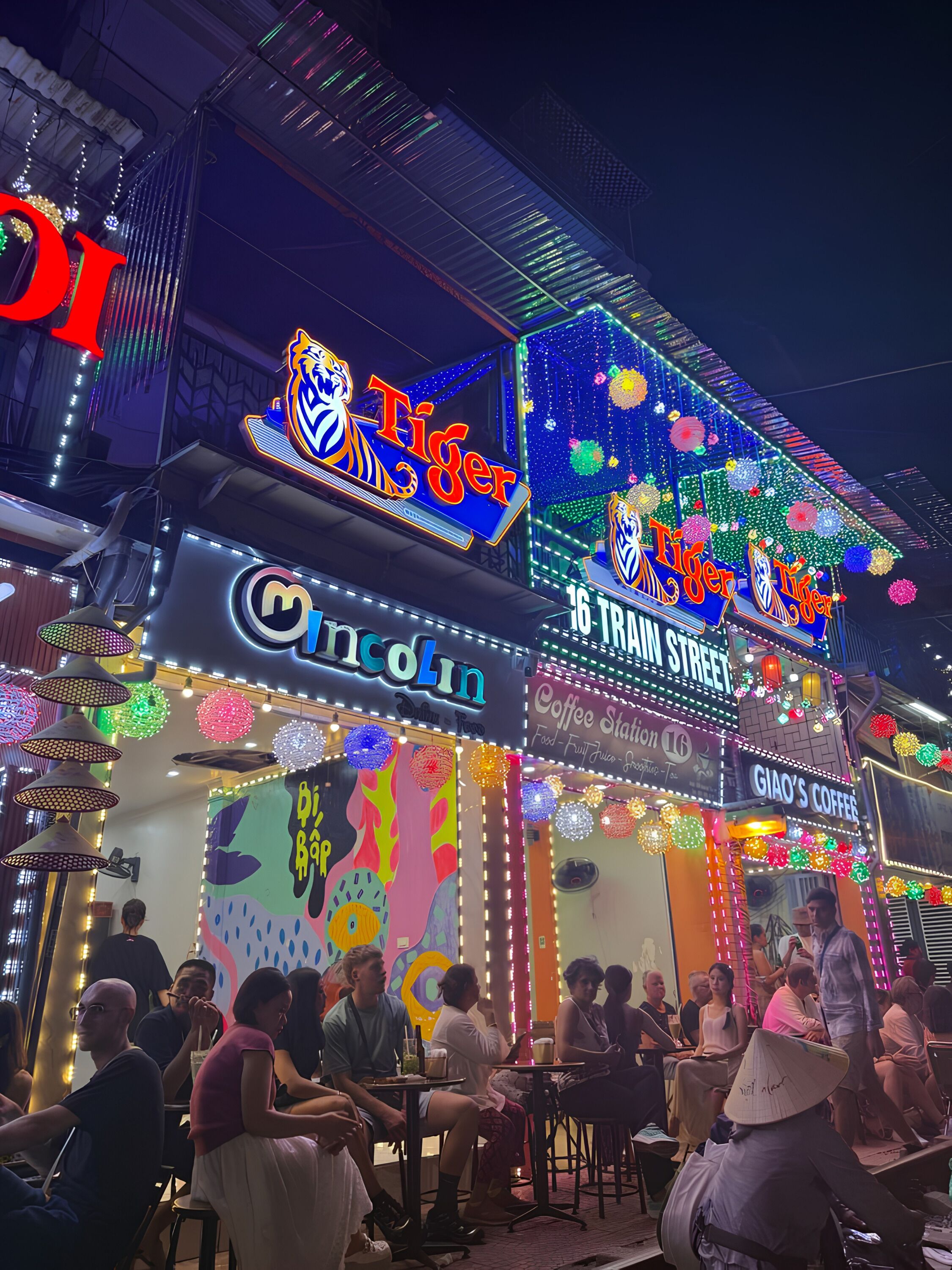 A building with illuminated signs for 'Tiger' and 'Lincoln' restaurants, a mural with colorful abstract art, and a 'Coffee Station' sign.