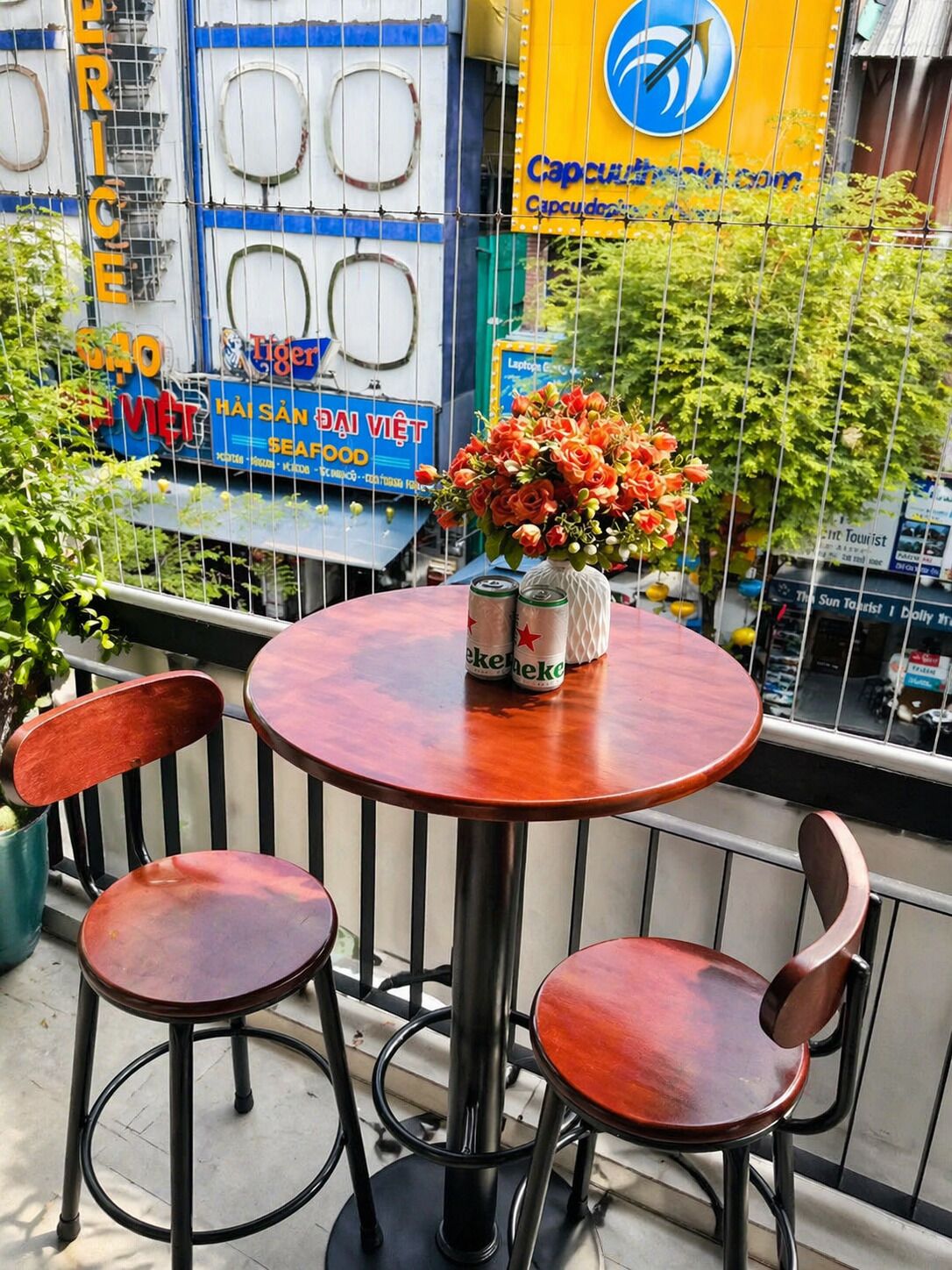 Un espace extérieur aménagé avec une table et des chaises, un vase de fleurs et une vue sur un bâtiment orné de différentes enseignes.