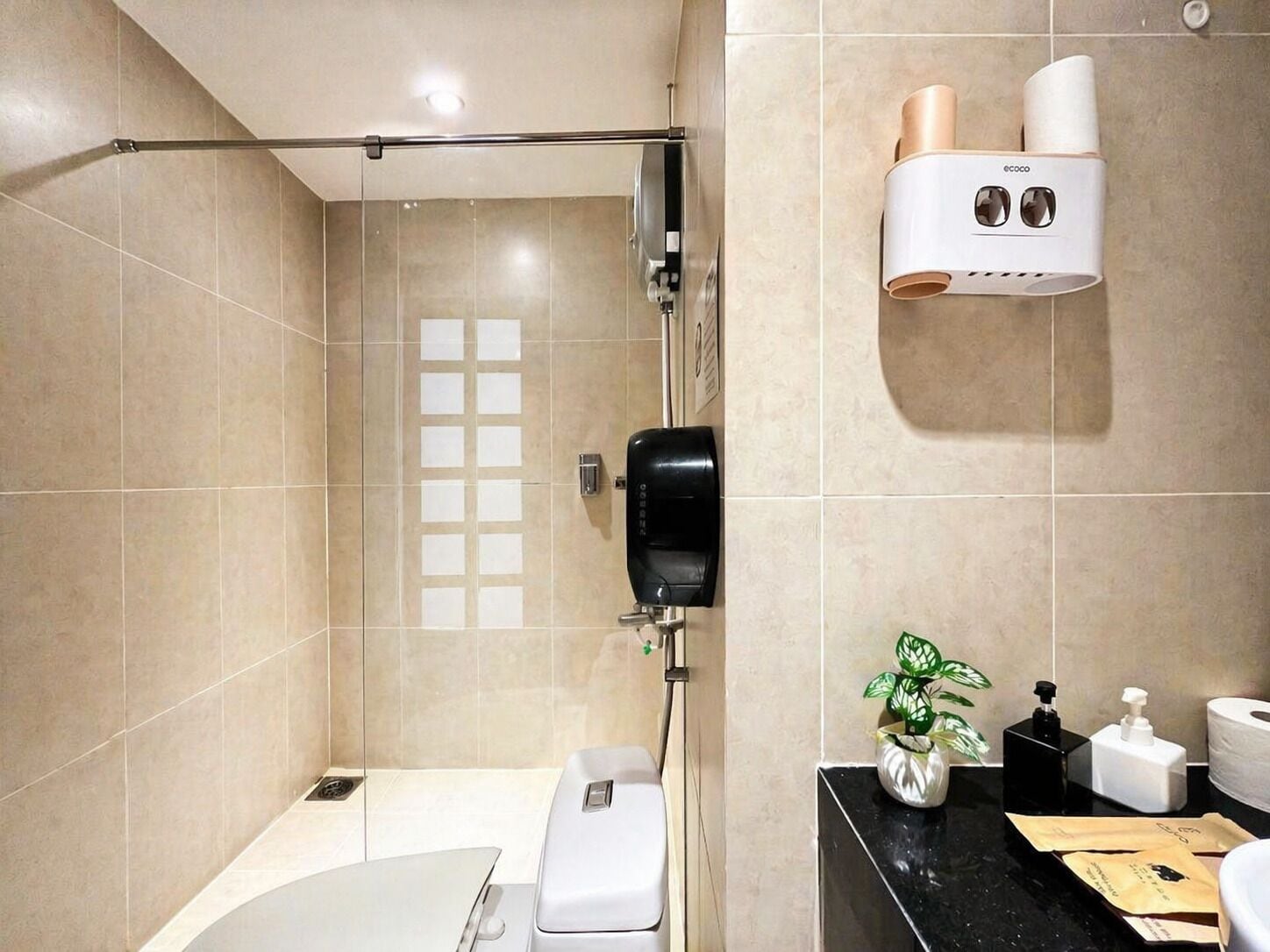 Ein modernes Badezimmer mit Dusche, Toilette und einem an der Wand montierten Fön.