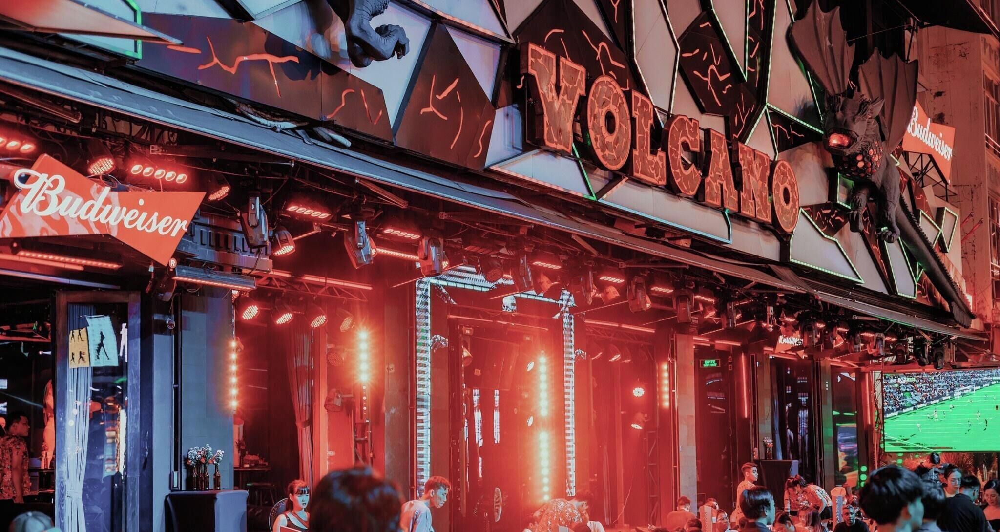 A venue with a neon sign reading 'VOLCANO' and a Budweiser sign.