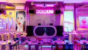 A futuristic interior with neon signage, a central projection screen, and tables set for dining. - Movida Stay - Bui Vien Walking Street, District 1 (Ho Chi Minh City)