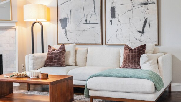 A living room with a sofa, coffee table, and abstract paintings on the wall.