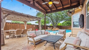 A covered patio with outdoor furniture, a pool, and a pergola.