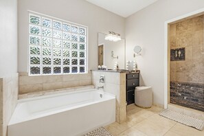 A bathroom with a bathtub, a vanity with a mirror, a window with a view, and a shower area. - Luxury Family Retreat • Saltwater Pool Oasis • BBQ (Frisco)