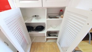 Una cocina compacta con armarios blancos, un lavamanos pequeño y una estufa.
