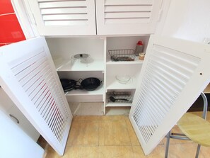 Een compacte keuken met witte kastjes, een klein spoelgedeelte en een fornuis.