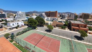 A tennis court with a net, surrounded by buildings and a clear sky. - TRAMUNTANA 325 STUDIO (Roses)
