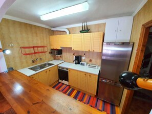 Una cocina compacta con armarios de madera, un refrigerador de acero inoxidable, una cafetera y un piso colorido a rayas.