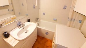 Une salle de bain équipée d’un lavabo, d’un miroir, d’une douche et de toilettes.